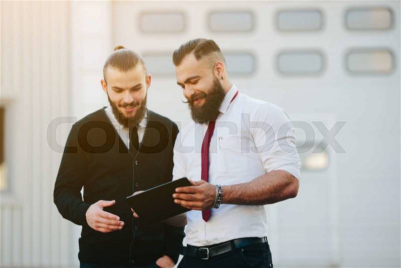 Two businessmen discussing something and looking at pad, stock photo