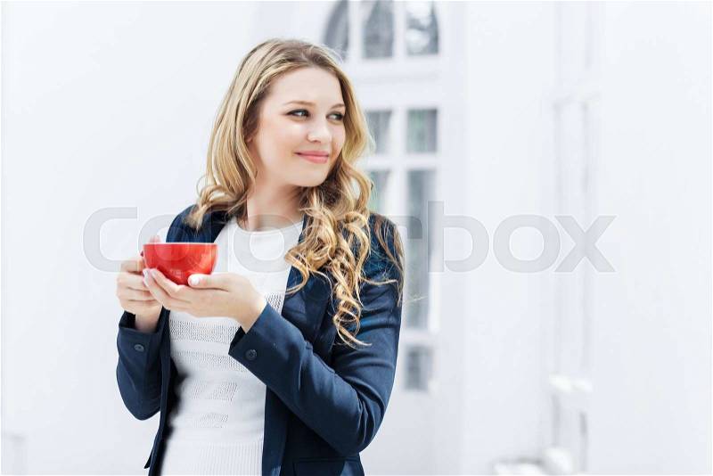 The smiling female office worker having coffee break in office, stock photo