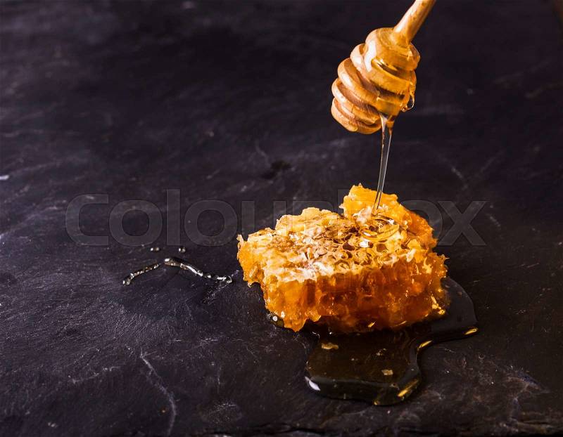 Honey drip and comb over black slate background, stock photo