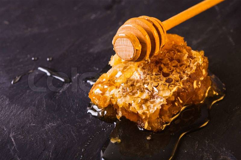 Honey drip and comb over black slate background, stock photo