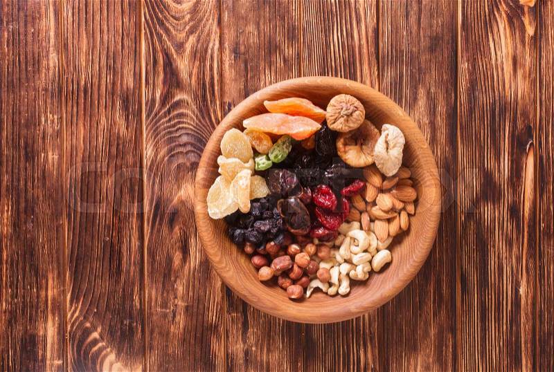 Dry fruits and nuts in bowl on wooden table. Copy space background - close up healthy sweets, stock photo