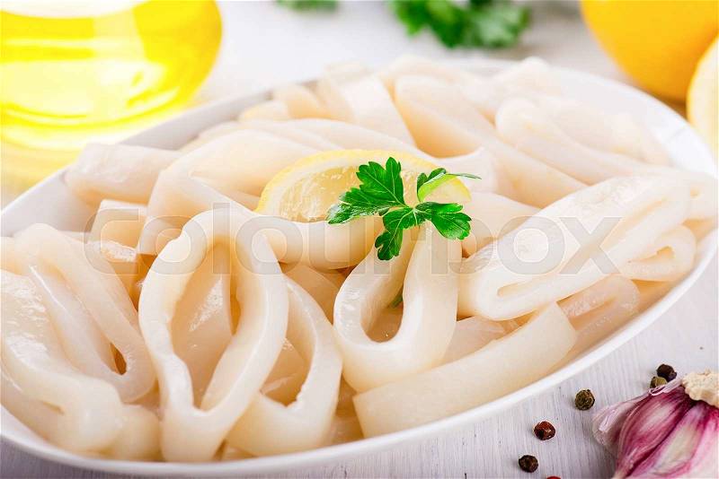 Raw squid rings on the white plate, ready to cook, stock photo