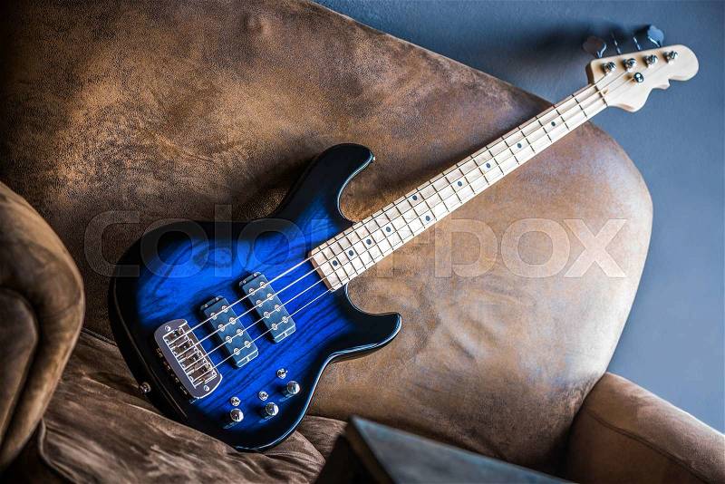 Bass Guitar Leaning Against a Couch. Blue Bass Guitar, stock photo