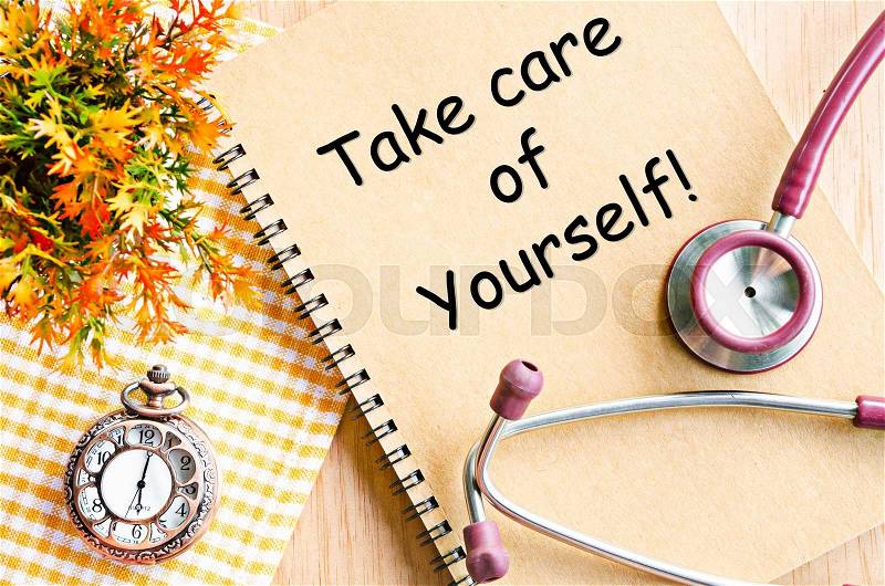 Take care of yourself on diary book and stethoscope with pocket watch on table, stock photo