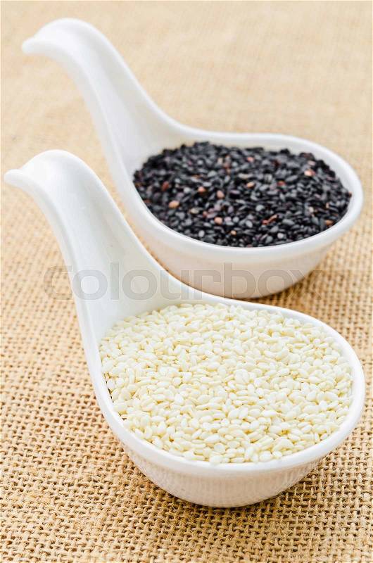 White sesame and black sesame seeds on white spoon, stock photo