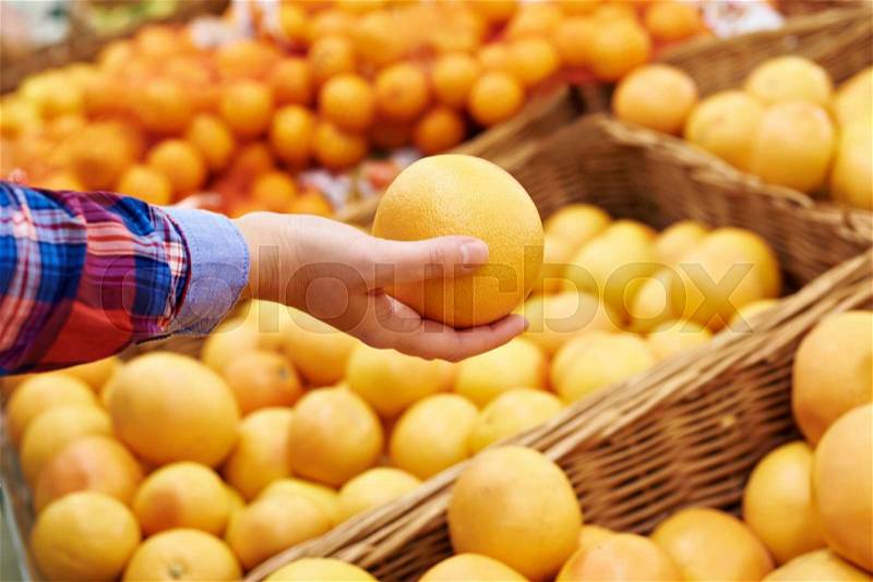Hand with grapefruit in fruit department in the supermarket, stock photo