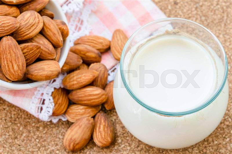 Almond milk in glass with almonds seeds on wood table, stock photo