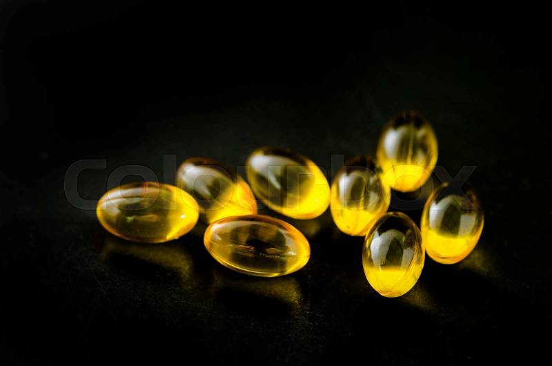 Fish oil omega 3 gel capsules, on black background, stock photo
