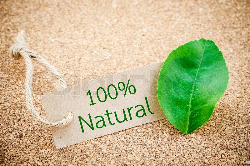 100% Natural word on recycle brown tag with green leaf on wooden background, stock photo