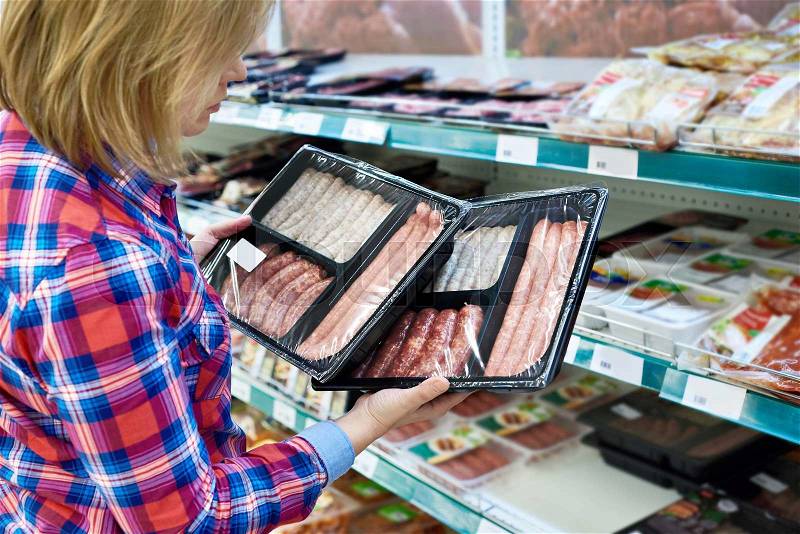 Woman chooses sausages for a barbecue in the store, stock photo