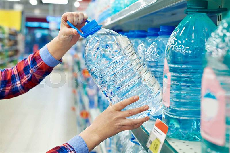 Woman buys bottle drinking water in shop, stock photo