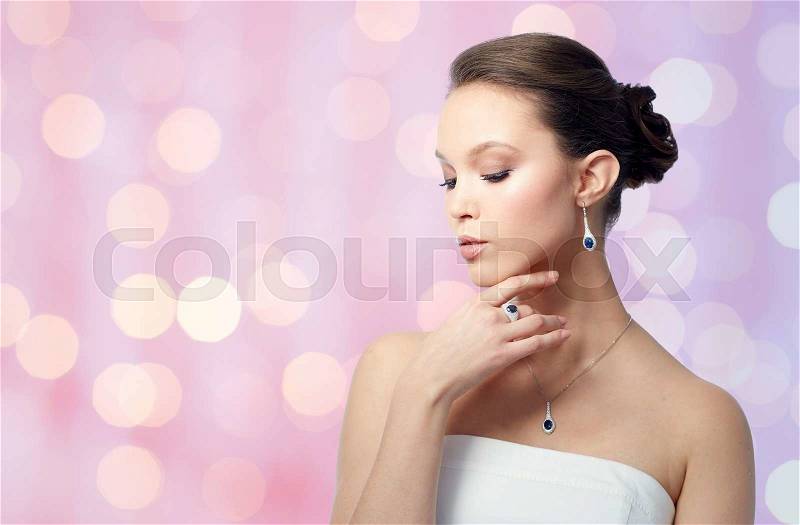 Beauty, jewelry, people and luxury concept - beautiful asian woman or bride with earring, finger ring and pendant over holidays lights background, stock photo