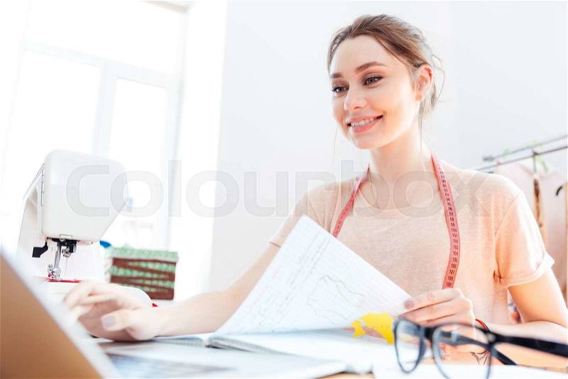 Portrait of happy beautiful young woman seamstress at work, stock photo