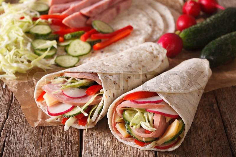 Sandwich roll filled with ham, cheese and fresh vegetables close-up on the table. horizontal , stock photo