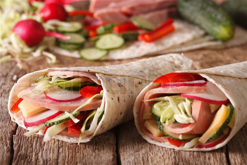 Tortilla Roll with ham and vegetables close-up and ingredients on the table. horizontal , stock photo