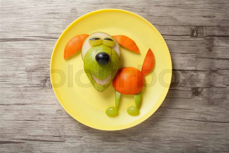 Dog made of juicy fruits on plate, stock photo