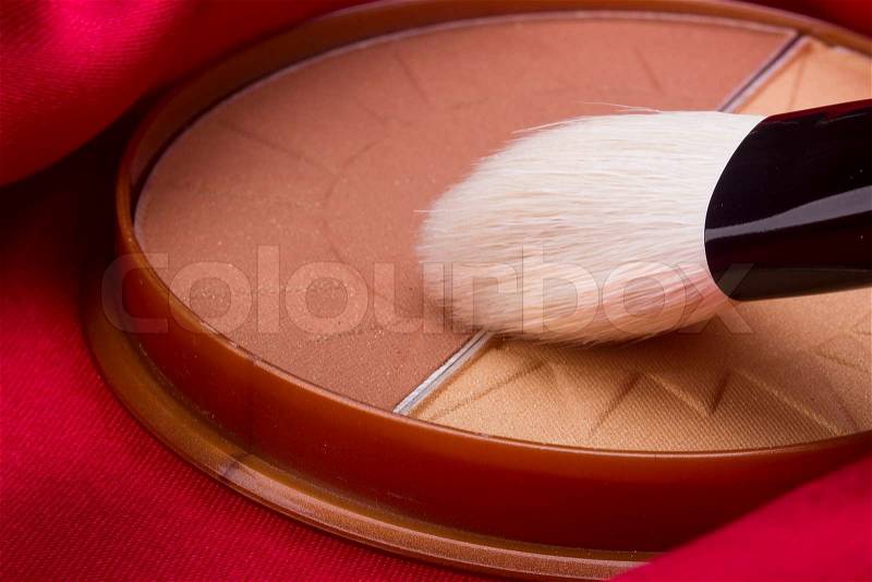 Powder brush and brown powder on a red background, stock photo