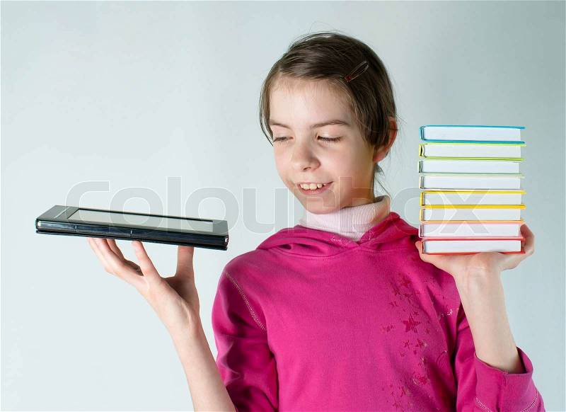 Teen girl holds electronic book in one hand and a stack of books in other, stock photo