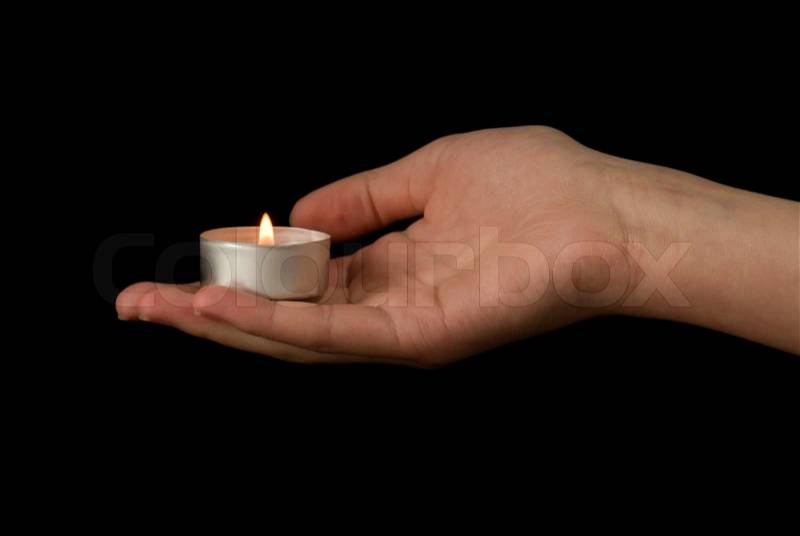Hand holding a candle on black background, stock photo