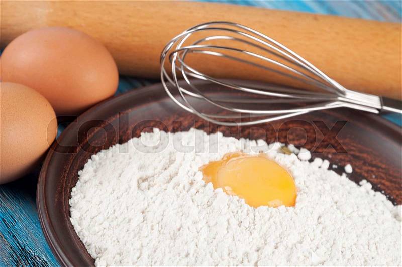 Eggs, flour and egg yolk on a blue wooden background, stock photo