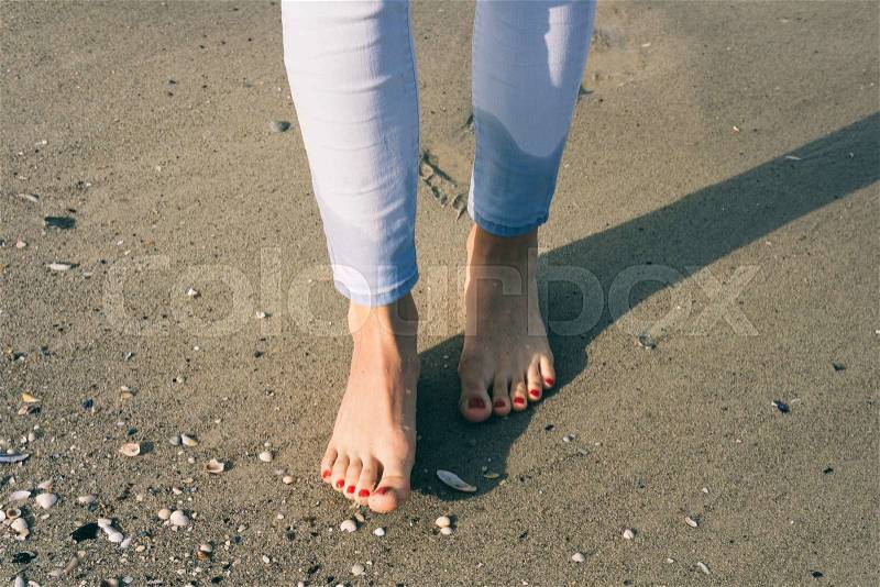 Bare female feet walking on wet sand at beach, stock photo