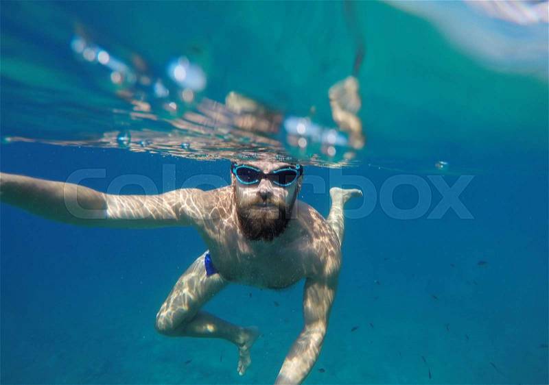Man doing underwater selfie shot with selfie stick in deep blue sea, stock photo