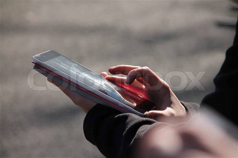 Busy lady on the street, holding the tablet pc in her hand and looks to the received message on the tablet, stock photo