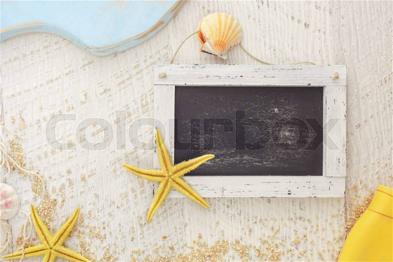 Summer holidays concept. Empty blackboard, different marine items and suntan lotion on rustic background. Top view, vintage toned image, blank space, stock photo