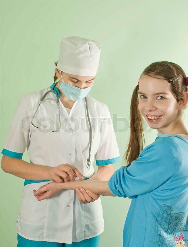 Lady doctor making an injection to smiling teen girl, stock photo