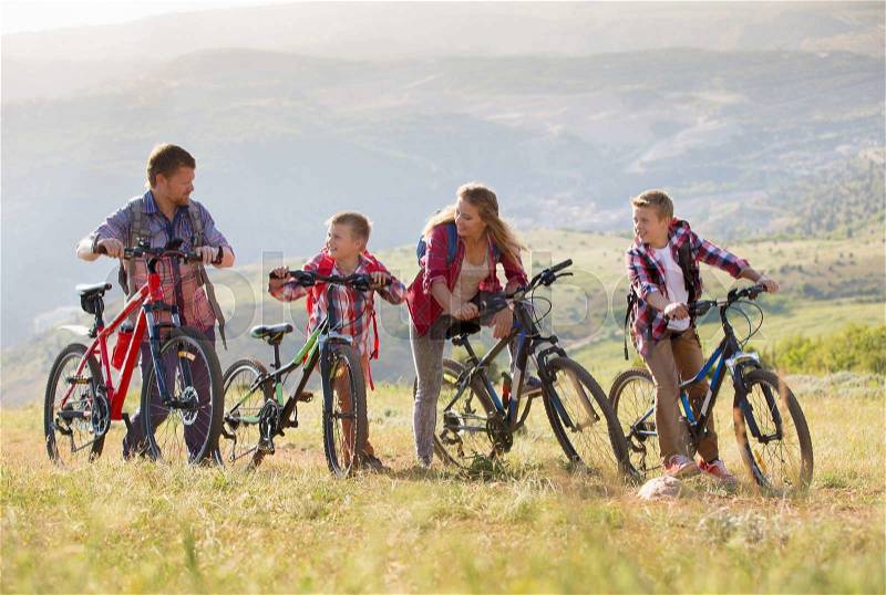 Family of four people riding bikes in the mountains, stock photo