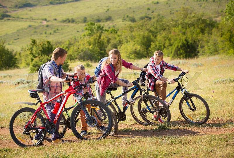 Family of four people riding bikes in the mountains, stock photo