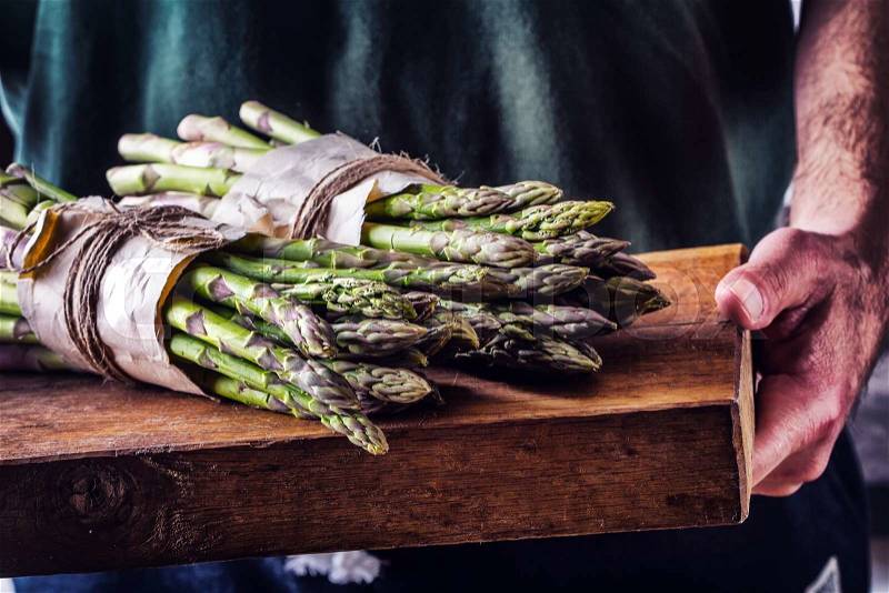 Asparagus. Raw asparagus. Fresh Asparagus.Green Asparagus. Tied asparagus in other positions. Farmer carries tied asparagus on a wooden board, stock photo