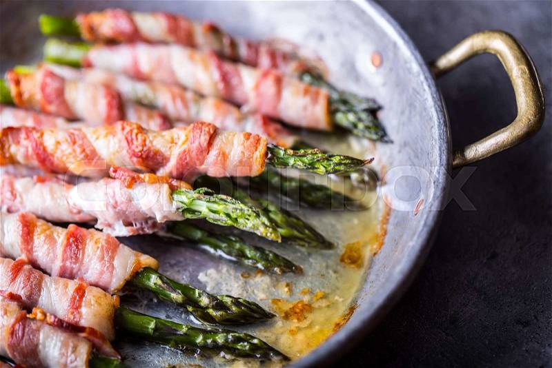 Asparagus. Asparagus and roll bacon. Grilled asparagus with rolled bacon and fried egg. Fried old pan full of rolled bacon with green asparagus and fried egg, stock photo