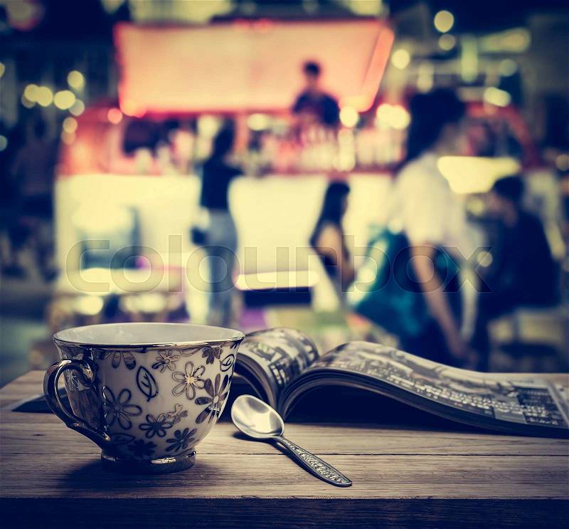 Coffee cup with magazine on wooden table in the night market, stock photo