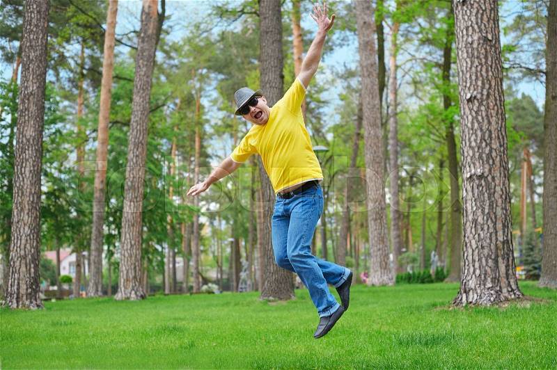 Cute man jumping in the park on sunny day, stock photo