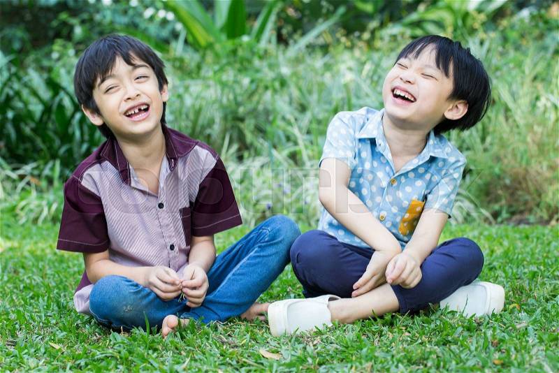 Two little happy boy sitting and laughing in park, stock photo