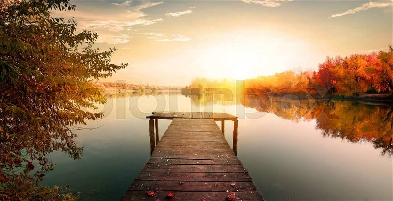 Red autumn and wooden fishing pier on river, stock photo