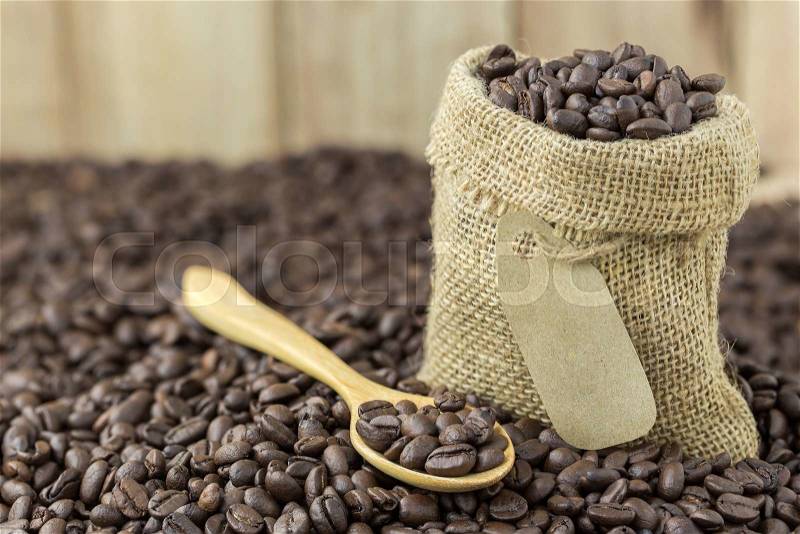 Coffee beans in sack bag and spoon on roasted coffee seed background, stock photo