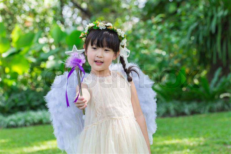 Little cute girl in angel dress with smiling face in the park, stock photo