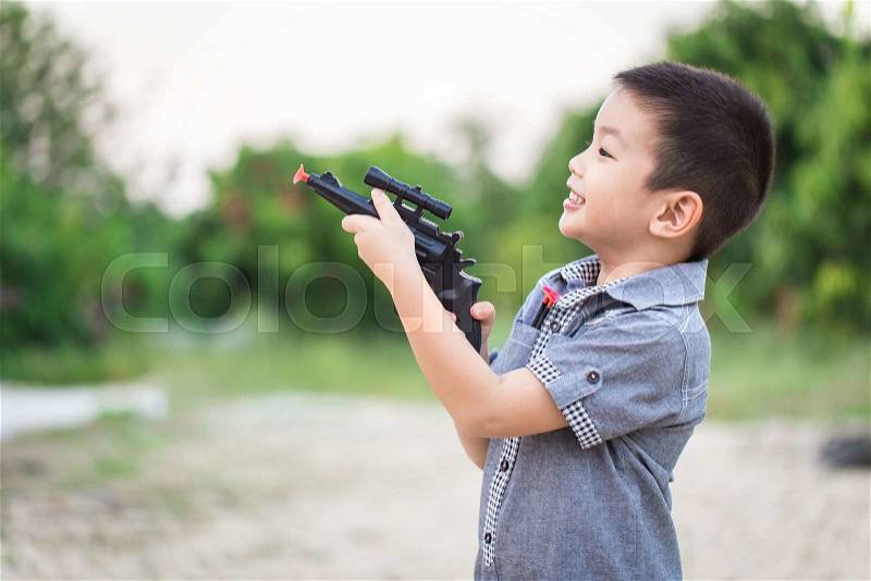 Little asian boy playing with a toy gun , stock photo