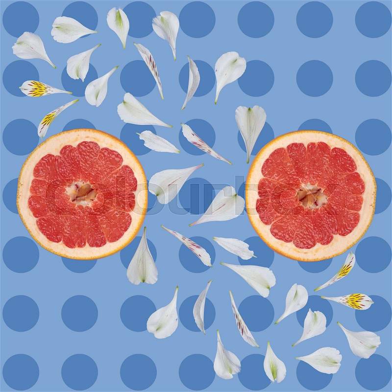 Grapefruit Against the background of circles and white flower petals on blue background, stock photo