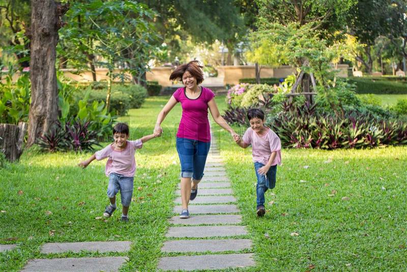 Mother running in the park with sons , stock photo