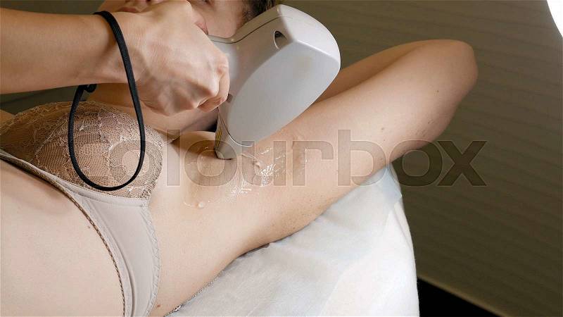 Woman gets laser hair removal treatment underarm. Modern permanent epilation procedure, stock photo