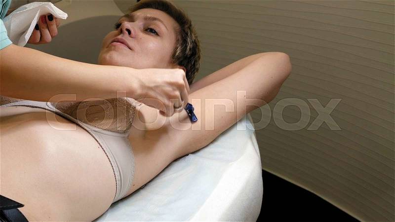 Doctor shaves woman\'s underarm before laser hair removal treatment. Modern permanent epilation procedure, stock photo