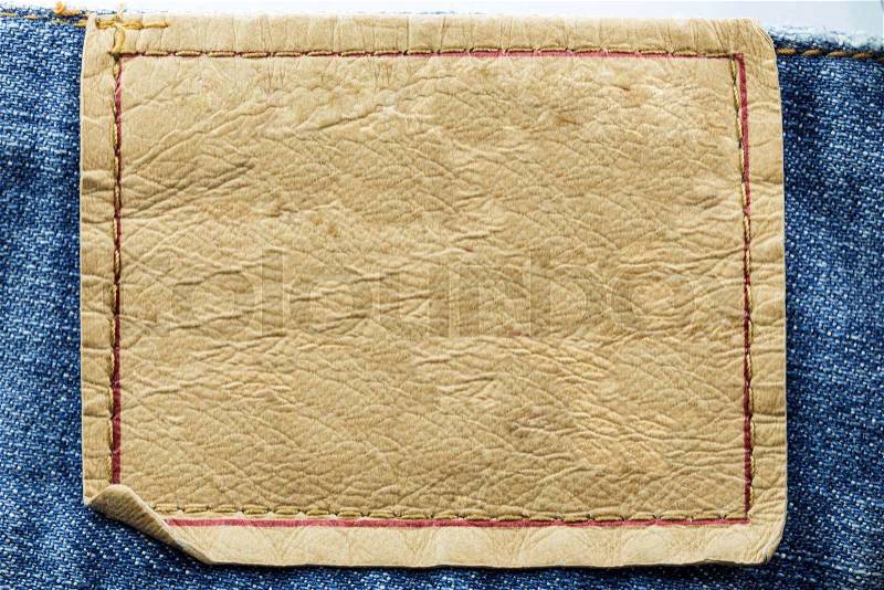 Blank leather jeans label sewed on a blue jeans isolated on white background, stock photo