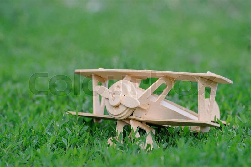 Closeup wooden plane toy on grass floor background, stock photo