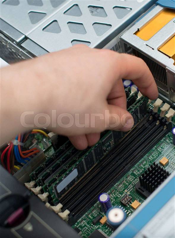 Computer technician installing RAM memory into motherboard, stock photo