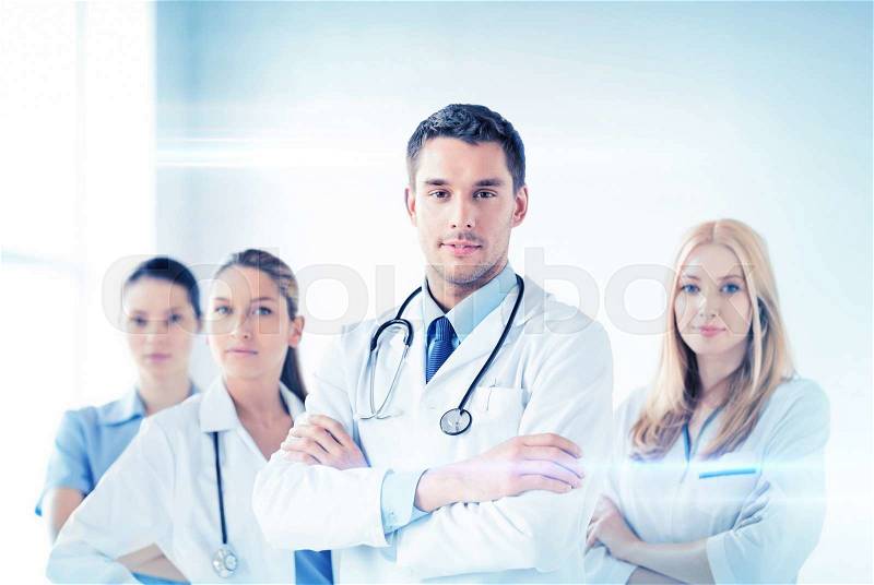 Attractive male doctor in front of medical group, stock photo