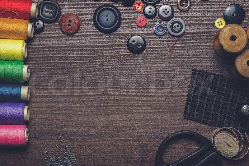 Buttons, needles and multicolored threads on the wooden table, stock photo