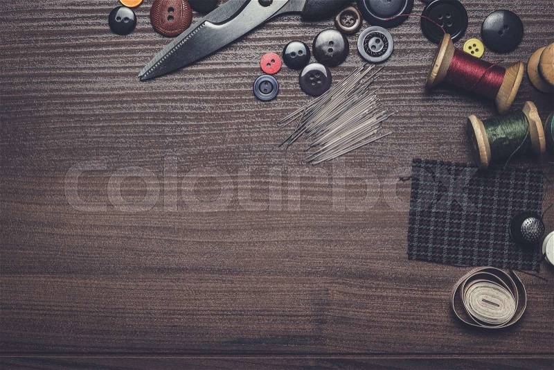 Needles threads and buttons on brown wooden table, stock photo